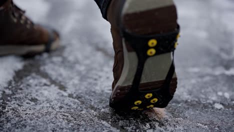 Ice-spikes-under-shoe-at-winter,-closeup-shallow-depth-slow-motion