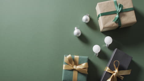 video of christmas presents and baubles with copy space on green background