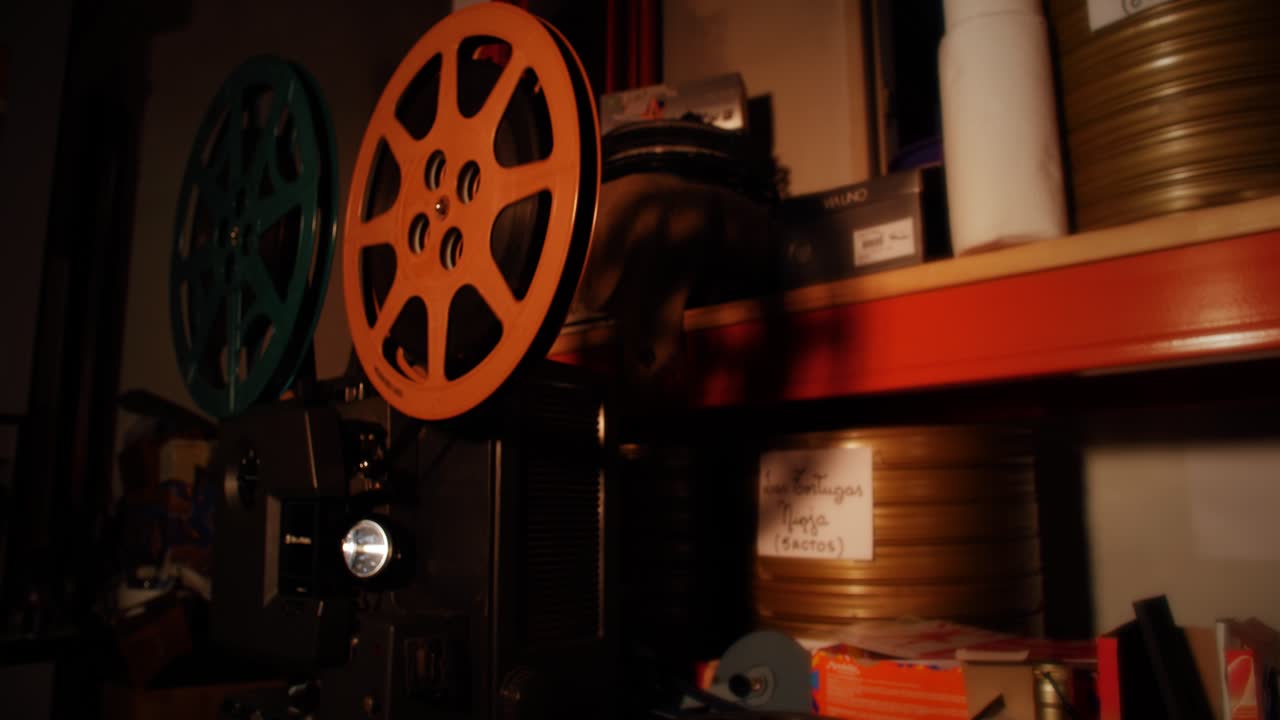 Proiettore cinematografico vintage con bobine che girano in una stanza buia