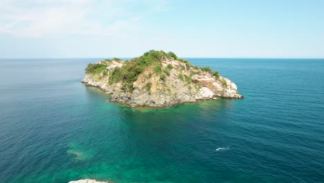 Kreisförmige-Luftaufnahme-Der-Insel-Gramvousa-Mit-Einer-Weißen-Kirche,-Umgeben-Vom-Mittelmeer,-Fliegenden-Vögeln,-Hohen-Berggipfeln,-Grüner-Vegetation,-Thassos,-Griechenland