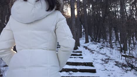 Tracking-shot-of-woman-climbing-up-snowy-stairs-in-a-mountain-during-winter