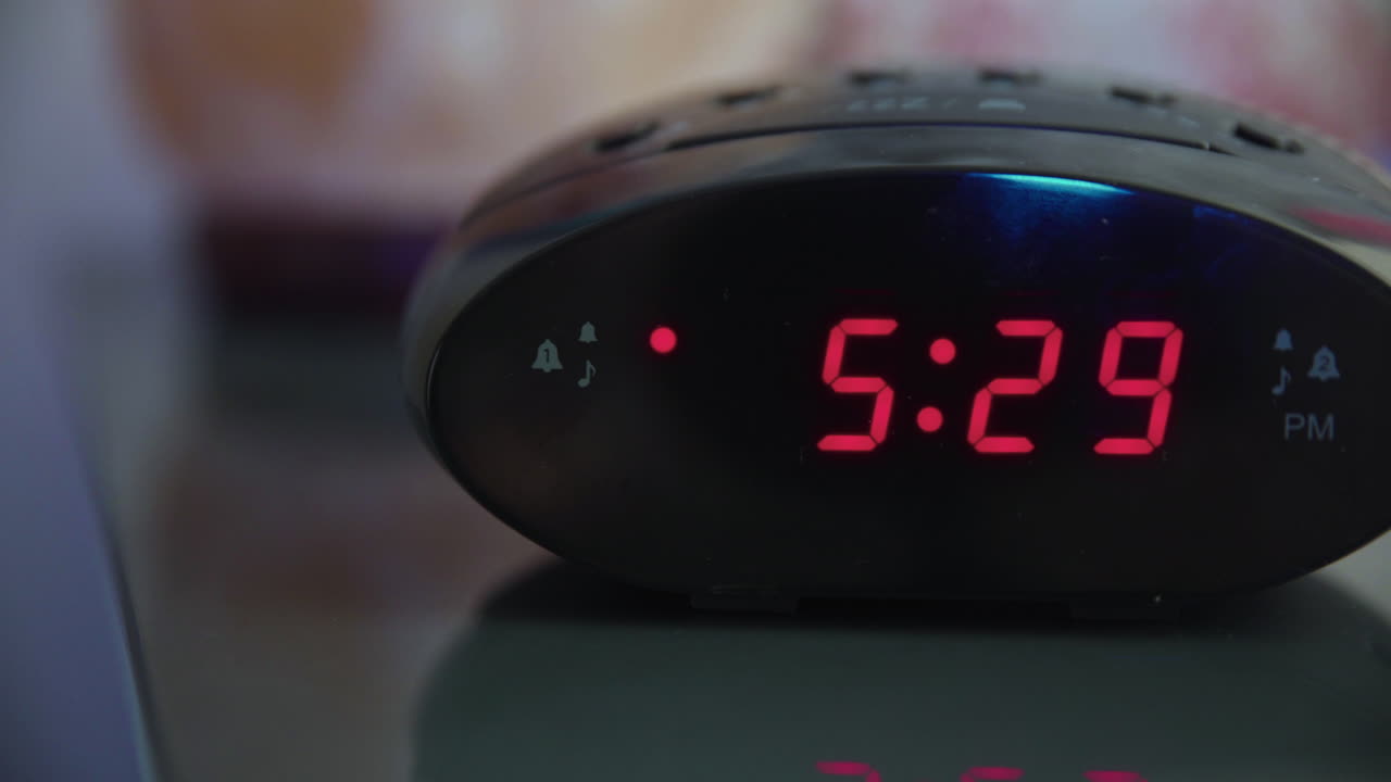 오전 5시 29분부터 5시 30분까지 알람 시계를 왼쪽에서 오른쪽으로 돌리고 알람을 끄려는 손이 졸린 듯 더듬거리고 있습니다.