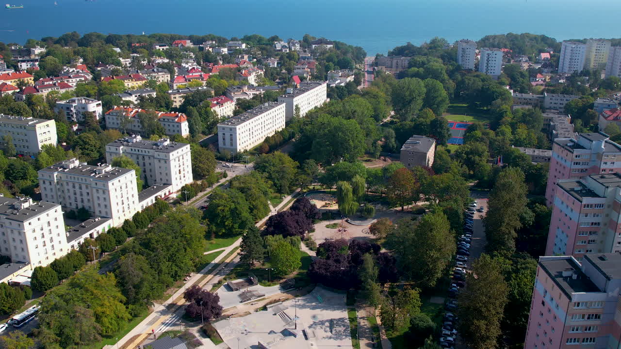 fotografía aérea al revés de un parque en una zona residencial de gdynia durante un día soleado con el mar báltico en el fondo