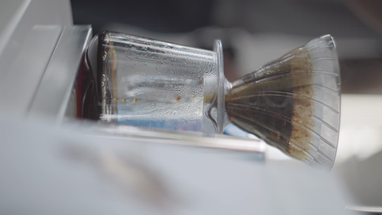 Vertical, coffee drips through filter slowly in modern kitchen, drop by drop