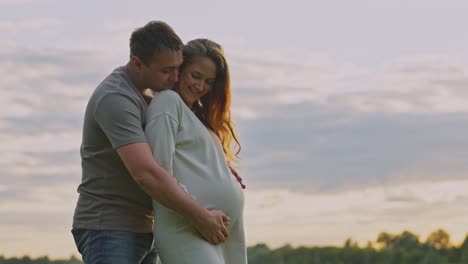 pregnant couple enjoying sunset