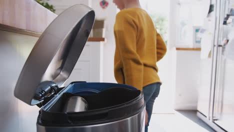 niño clasificando el reciclaje en el contenedor de la cocina en casa