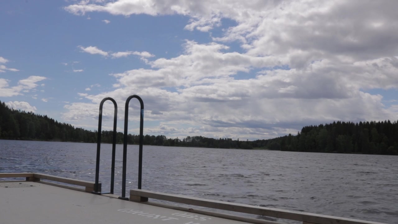 Wide shot of wooden bathing pier with ladder on calm waters of Sognsvann lake