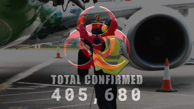 Digital composite video of hazard sign with Total Confirmed number rising against mid airport worker