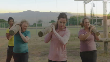 carrying logs on shoulders, women doing outdoor fitness training session