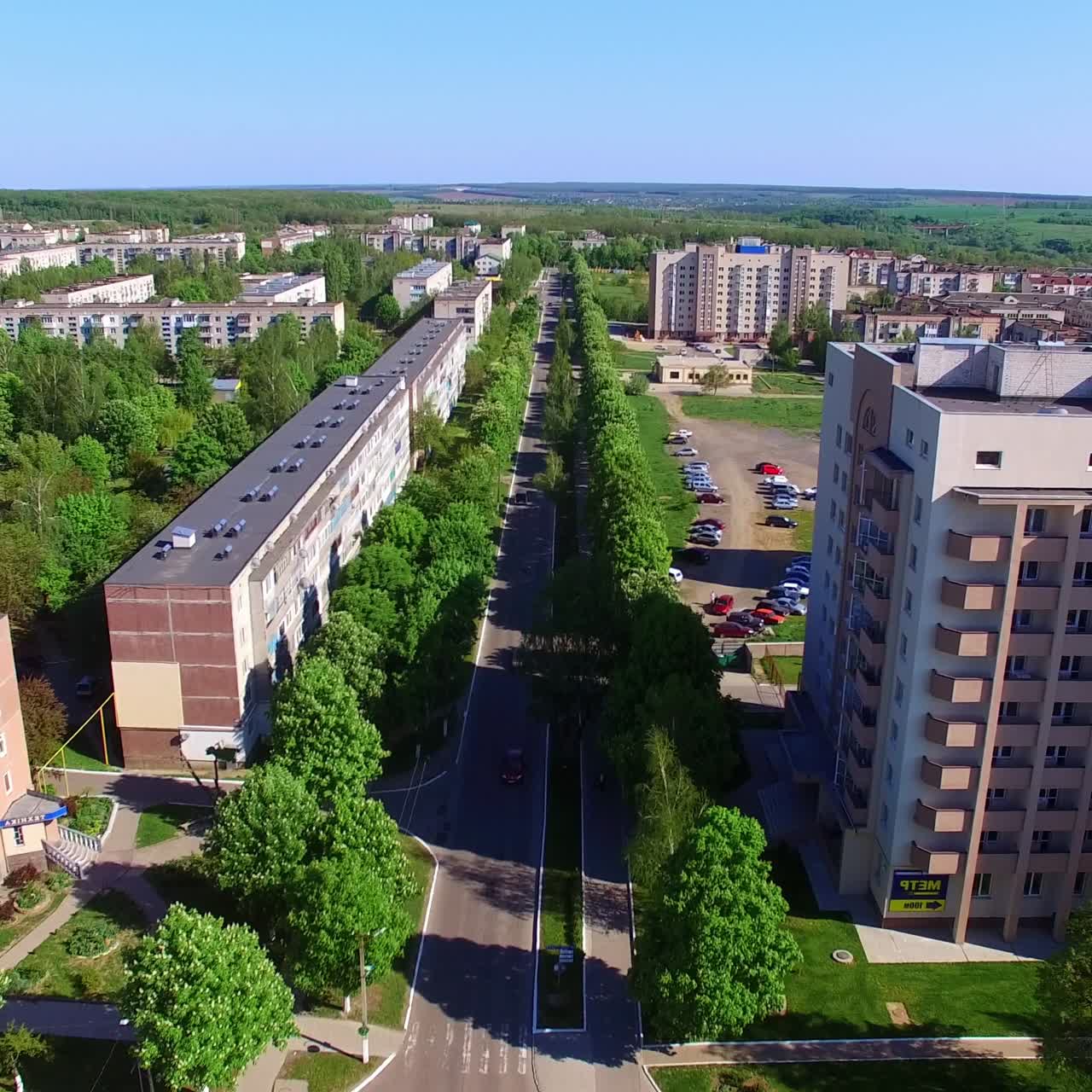 Empty crossroads in the modern Ukrainian city. Drone shot rising over the city on summer day. Green nature at backdrop
