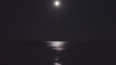 still shot of a calm sea lit by a moonlight