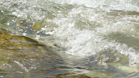 el agua potable cristalina fluye entre las piedras de un río a la luz del sol