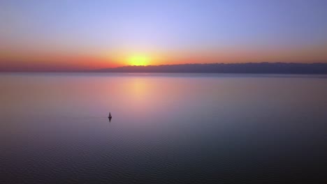 aerial drone footage of an enormous lake at sunset, the stunning colours and the impressive mountains in the background