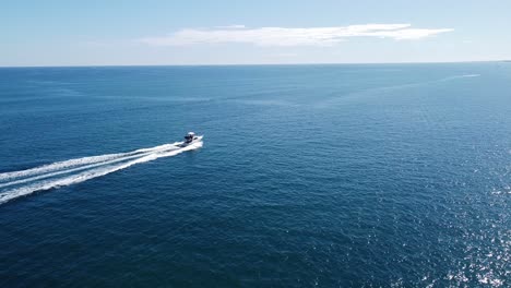 Aerial-Tracking-Shot-Of-Small-White-Yacht-Travelling-Fast-On-Calm-Sea