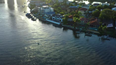 Main-canal-on-the-Gold-Coast-Early-Morning-rowers,-on-shimmering-water