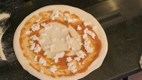 Close-Up-Of-An-Unrecognizable-Chef-Picking-Up-A-Pizza-With-A-Metal-Peel-To-Place-It-In-The-Oven-In-A-Restaurant-Kitchen