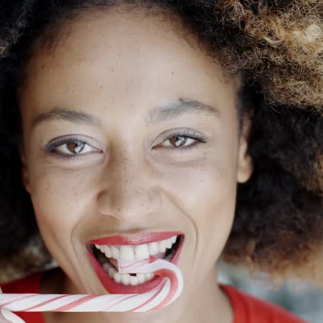 mujer joven mordiendo un bastón de caramelo festivo