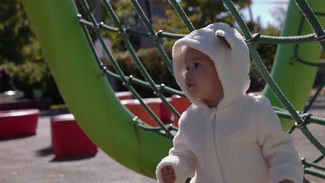 young toddler girl explores outdoor play structure park on sunny brisk autumn day - medium shot