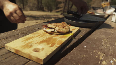 close up camper uses the knife to cuts the english muffin sandwich in half