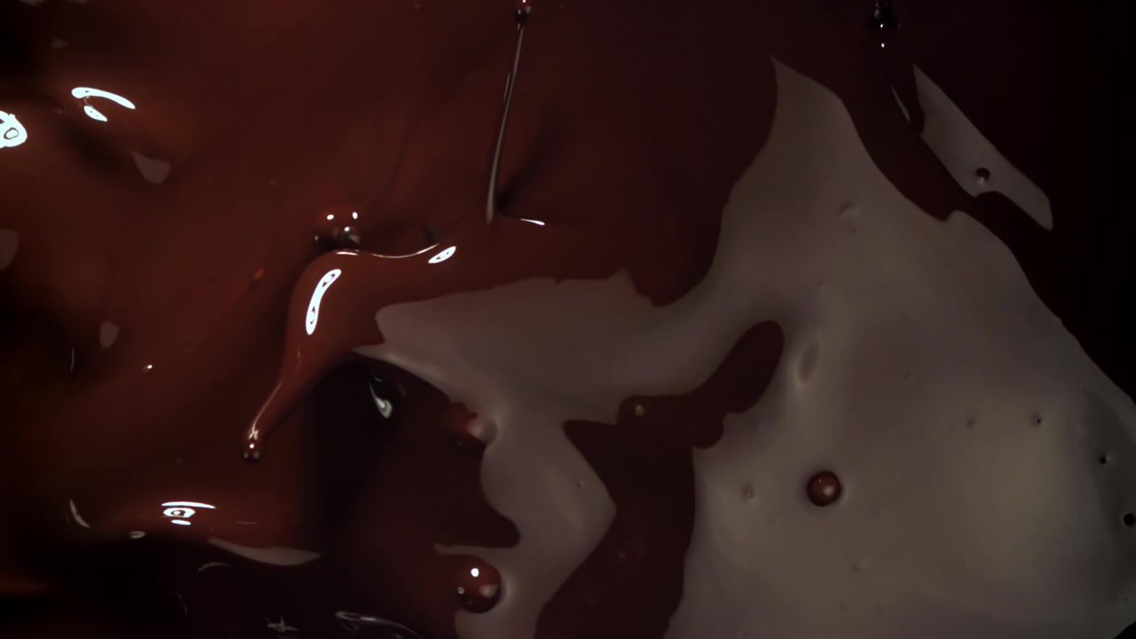 Chocolate negro derretido y espeso goteando y formando remolinos en cámara lenta