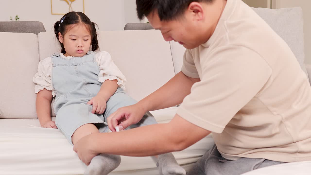 Father Applying Bandage to Daughter's Knee