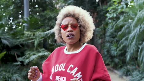 woman with blonde afro and heart sunglasses