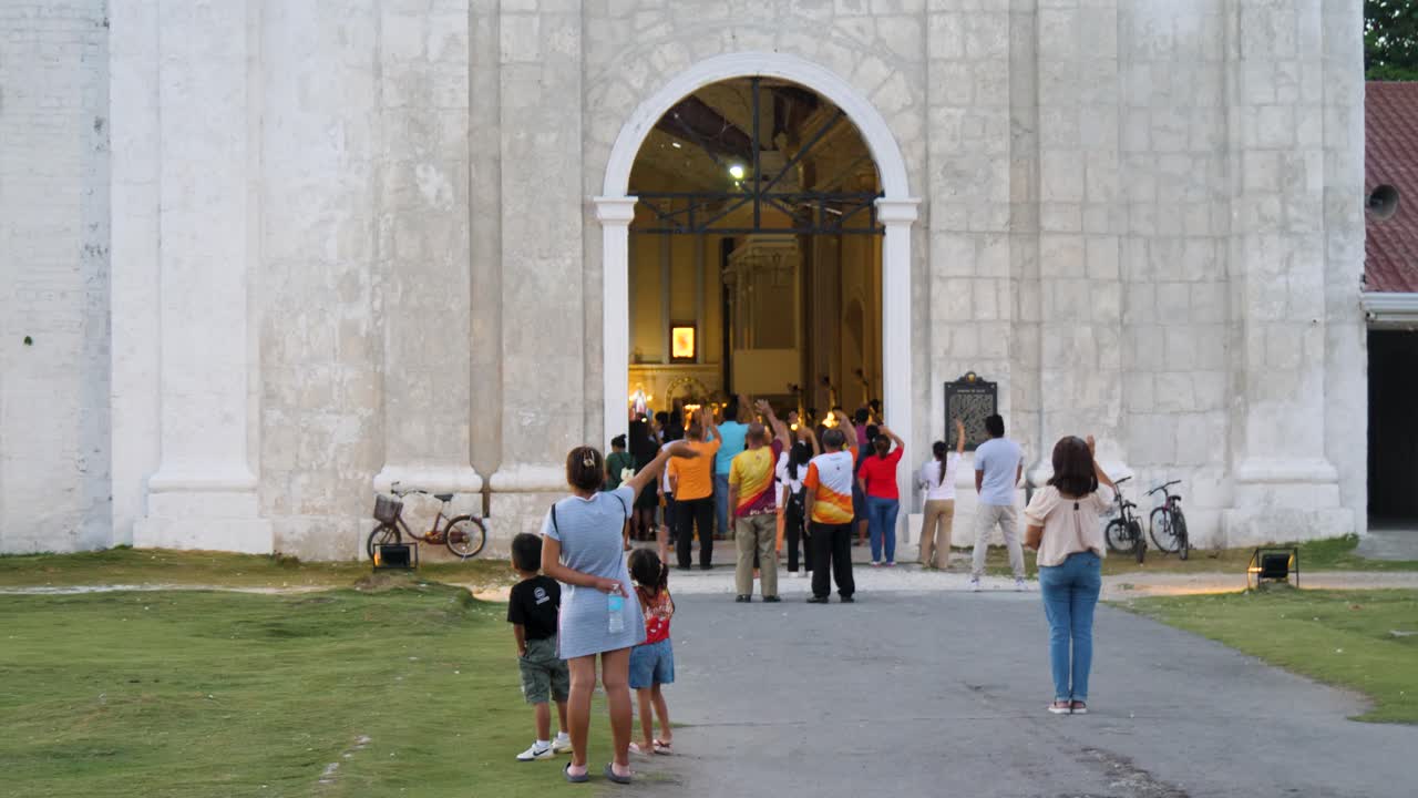 At entrance, where prayers ascend, Churchgoers’ hands in faith extend