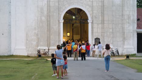 at entrance, where prayers ascend, churchgoers’ hands in faith extend