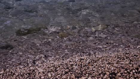 Vacaciones-Soleadas-De-Verano:-Aguas-Cristalinas-Que-Bañan-Suavemente-La-Costa-Cubierta-De-Guijarros,-Invitando-A-La-Tranquilidad-Y-La-Felicidad-Refrescante.