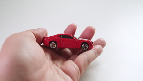 Revealing-a-red-sports-car-toy-hidden-between-the-palms-of-two-hands,-and-carefully-checked-by-its-owner