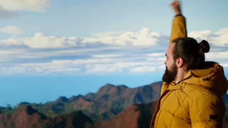 triumphant hiker stands at the mountain peak with his arms raised in victory