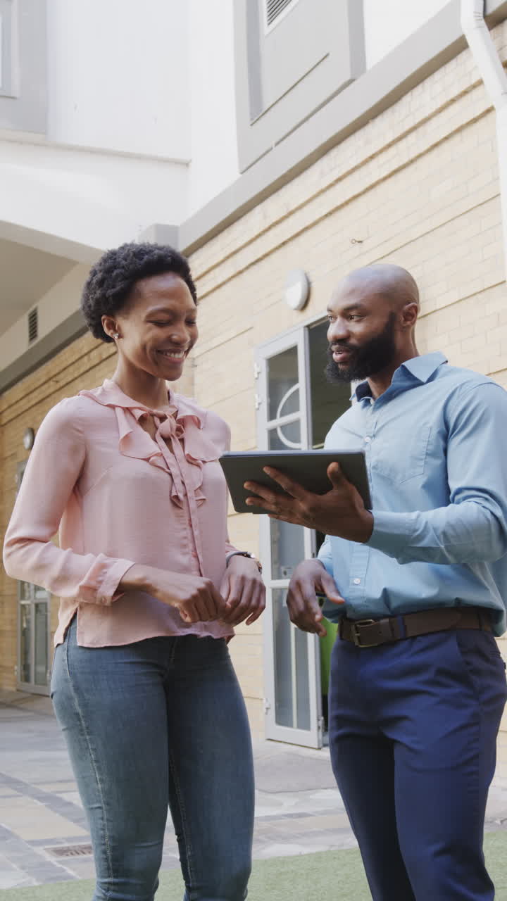 Vídeo vertical de profissionais afro-americanos conversando e usando tablet em câmera lenta