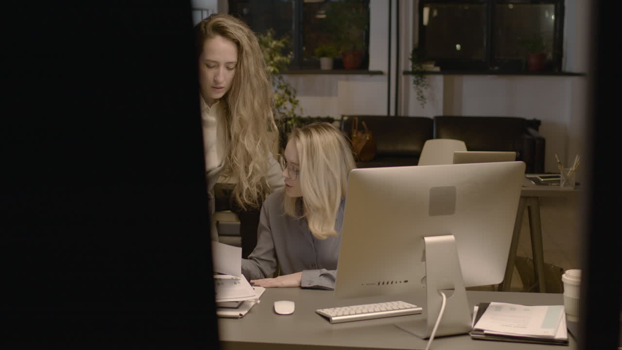 Two Female Employees Talking Together And Checking Reports In The Office