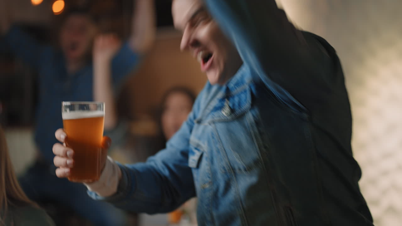 Group of male and female friends fans celebrating whilst watching game on TV screen in sports bar or pub
