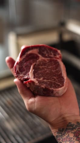 raw steak in hand ready for grilling