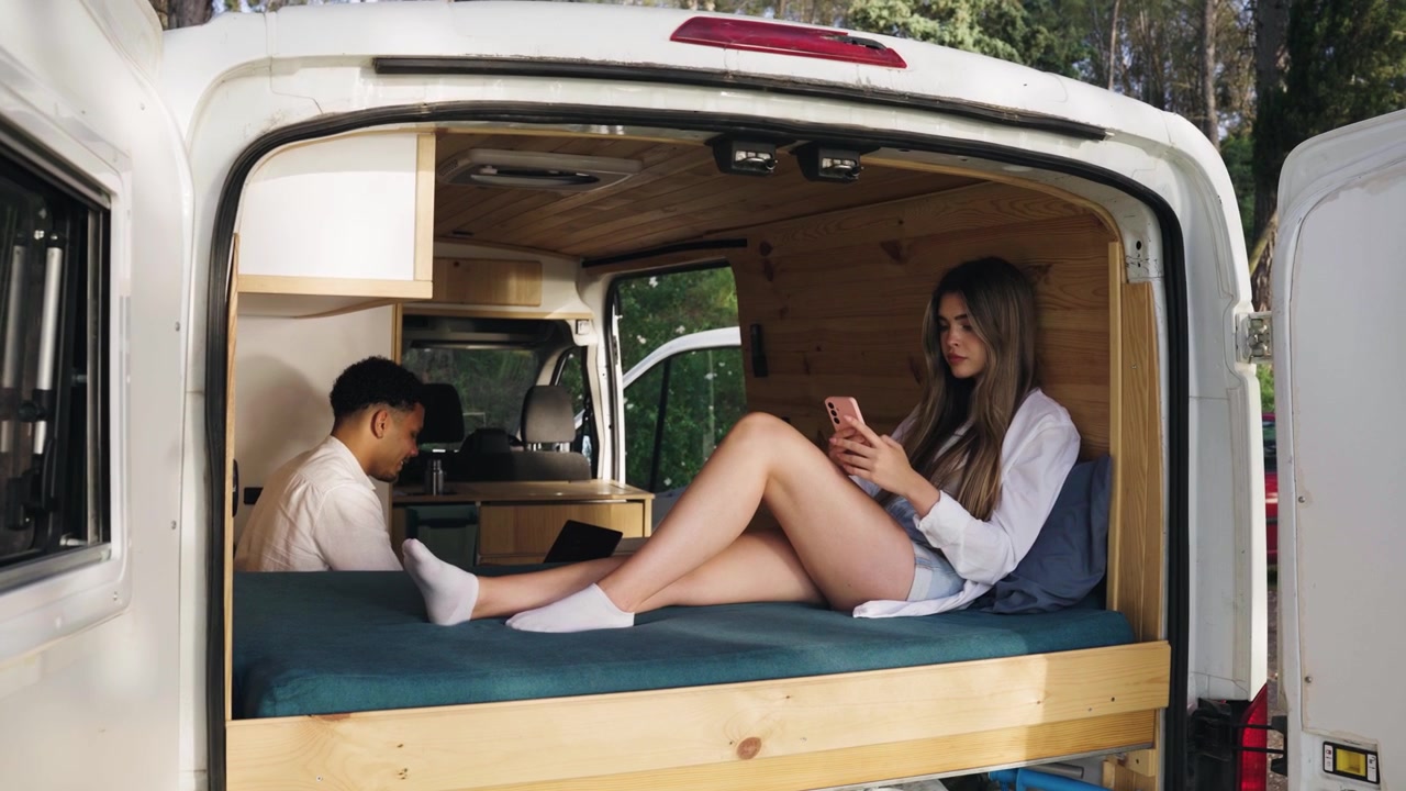 Young Couple Relaxing and Working in a Converted Camper Van
