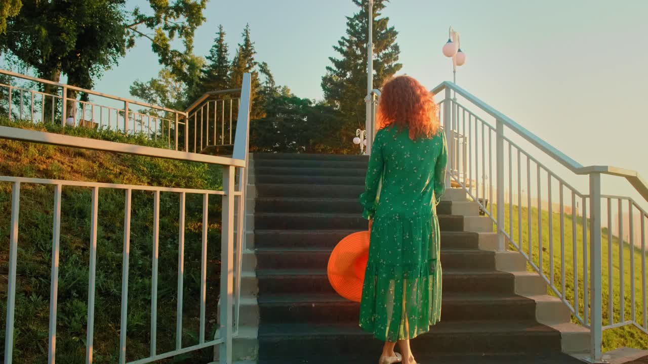 Woman walking down stairs in a green dress