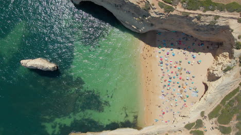 aerial view of crowded praia do carvalho in algarve, portugal with umbrellas on the sand during a sunny summer day