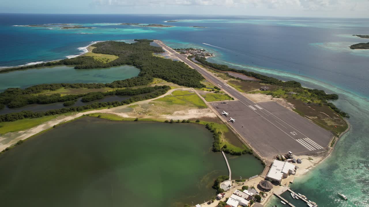 Gran roque runway, tropical island, sea, and approaching airplane in motion, aerial view