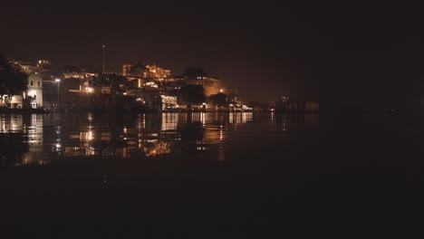 royal palace warmly lit at night reflecting in the lake water with soft rippling waves.