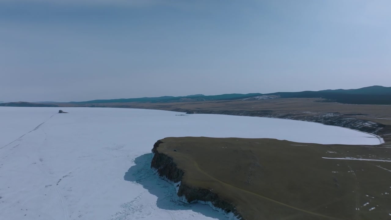 Droneoptagelser af Kharantsy-kappet ved Bajkalsøens frosne kystlinje, Irkutsk oblast, Rusland, med snedækkede ismarker, klipper og steppelandskab