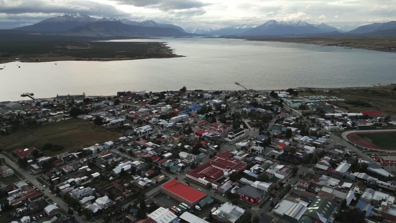 칠레 푸에르토 나탈레스 시, 목가적인 만 물과 안데스 코르디예라 배경의 파타고니아 풍경 사이에 있는 마을 건물 위의 공중 드론