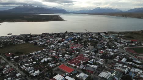 city of puerto natales chile, aerial drone above town buildings amongst patagonian landscape of idyllic bay water and andean cordillera background