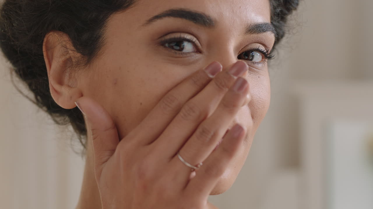 retrato de una hermosa mujer joven mirándose en el espejo con una piel perfecta y saludable tocando la cara con las manos disfrutando de una tez natural suave con cuidado de la piel antienvejecimiento preparándose en casa concepto de belleza