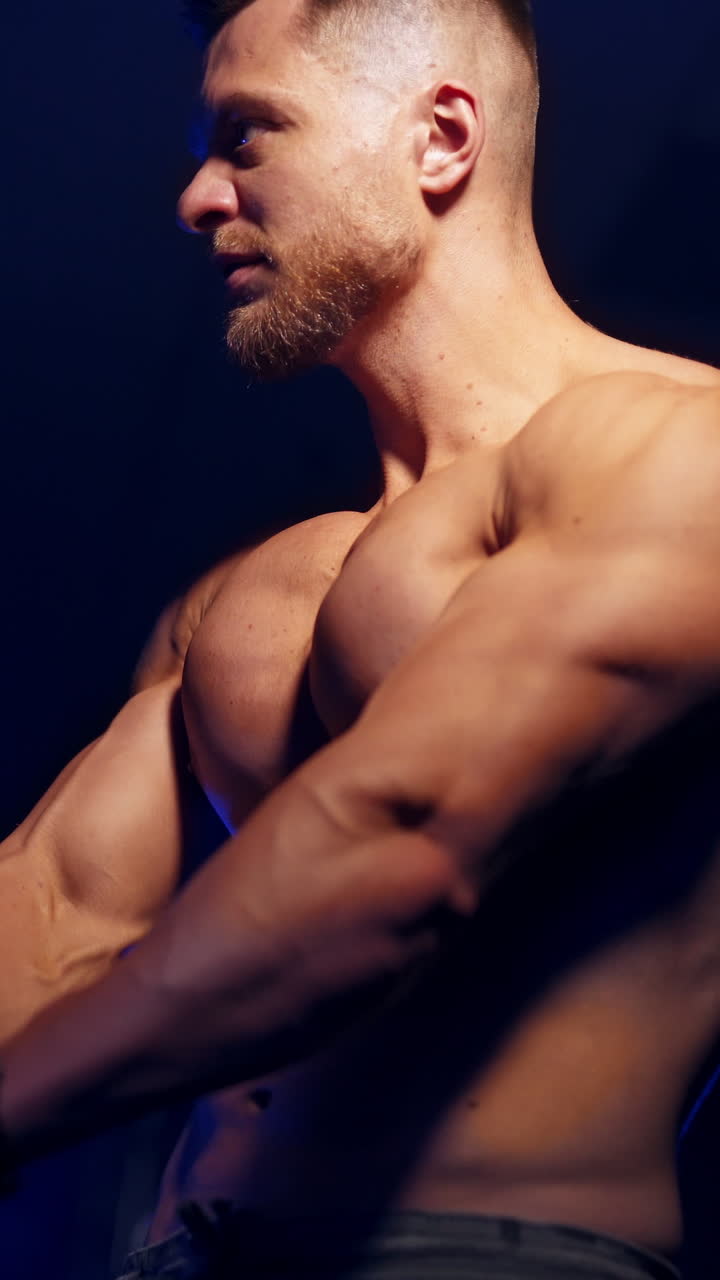 Handsome athletic sportsman. Strong muscular bodybuilder athlete man posing at gym. Vertical video