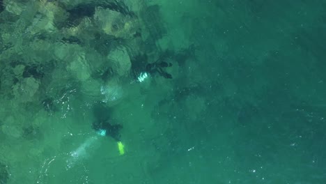 unique view of scuba divers below the water exploring a man-made artificial reef with bubbles breaking the ocean surface