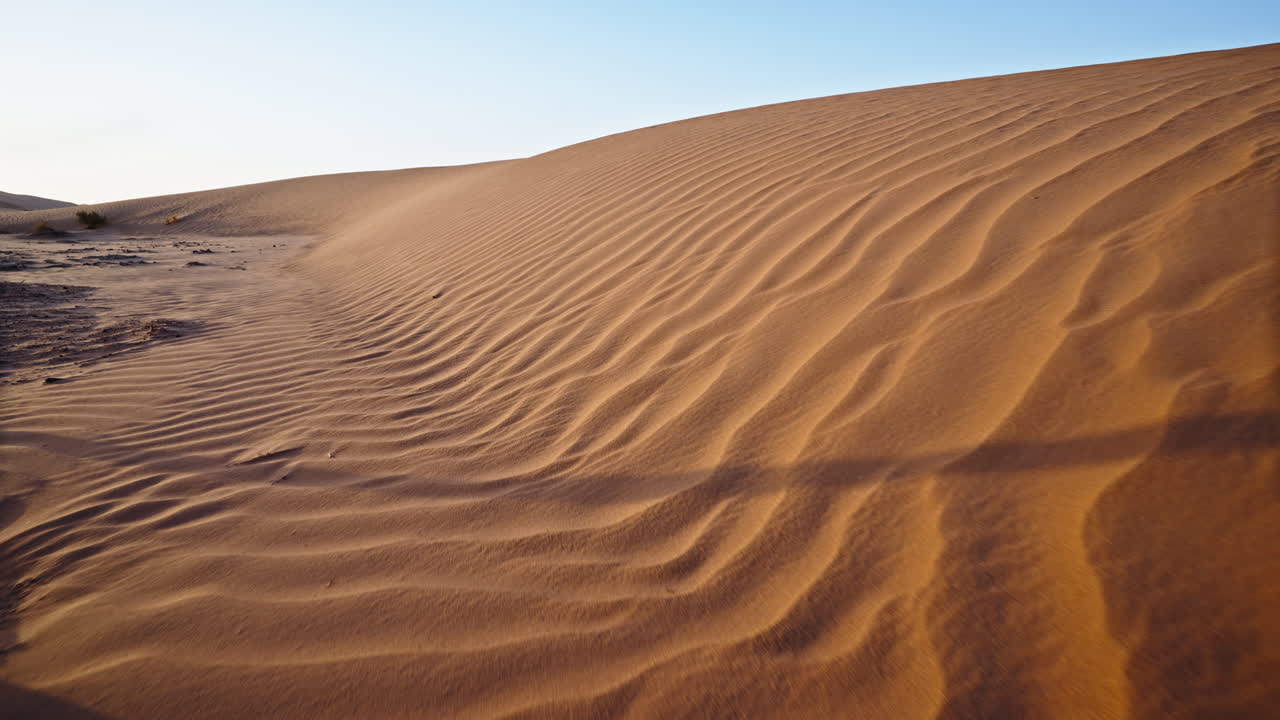 dunas de arena doradas con ondas bajo un cielo despejado al atardecer