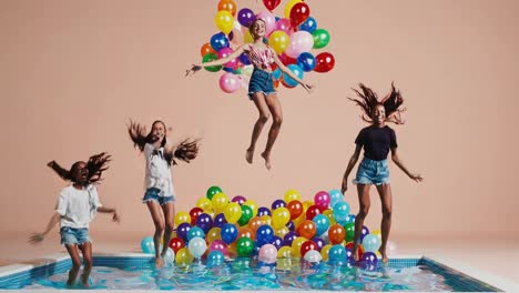 girls jumping in a pool with balloons