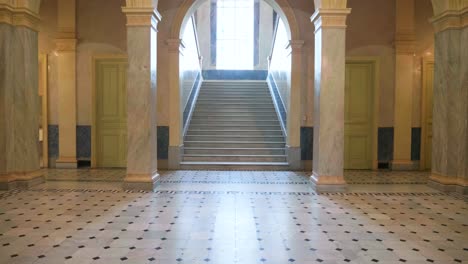 enorme sala de la villa de mármol con columnas y escalera soleada