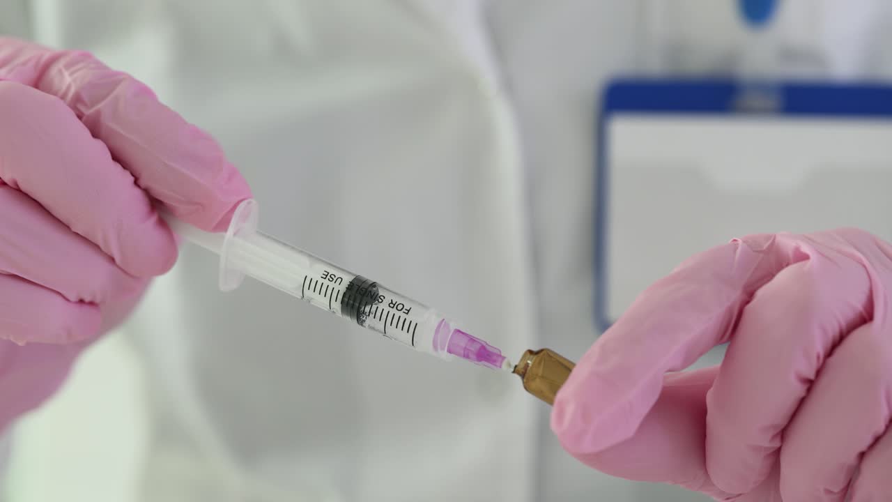 Medical professional preparing an injection with a syringe and ampule